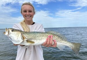 A woman holding a fish on top of the water.